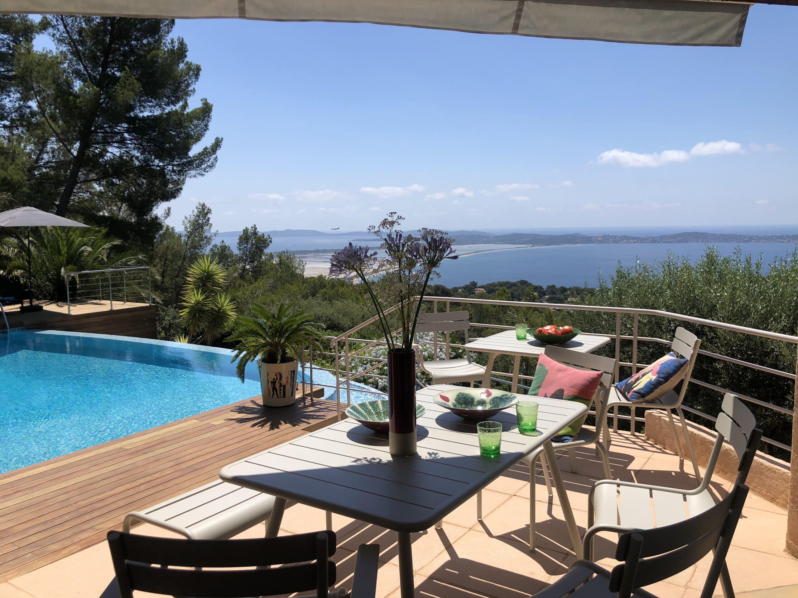 Terrasse moderne avec table dressée, piscine à débordement et vue panoramique sur la mer Méditerranée.