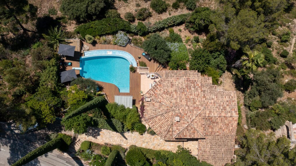 Villa de luxe avec piscine et jardin : Vue aérienne Vue aérienne d'une villa de luxe avec piscine turquoise, terrasse en bois et jardin méditerranéen luxuriant.